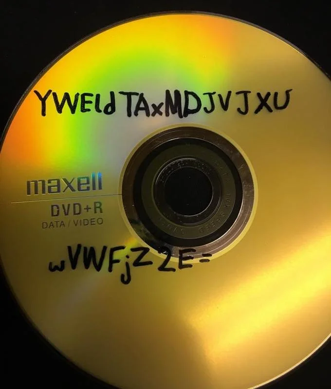 11B X 1371 — Gold DVD with handwritten encrypted text and cipher codes written across its surface.