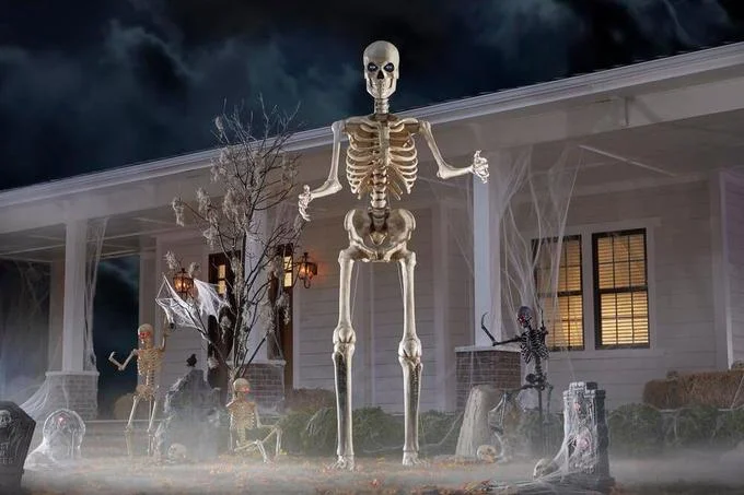 12 Foot Tall Home Depot Skeleton — Professional product photo of the 12-foot Home Depot skeleton displayed in front of a house with Halloween decorations, fog