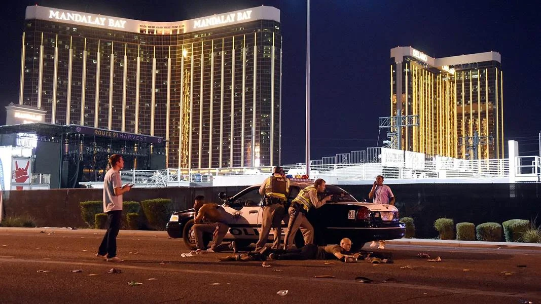 2017 Las Vegas Strip Shooting — Police officers and civilians take cover behind a squad car on the Las Vegas Strip near the Mandalay Bay hotel during the 2017