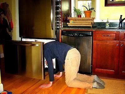 241543903 Heads In Freezers — Photograph from above showing an individual bending forward with head inserted in refrigerator.