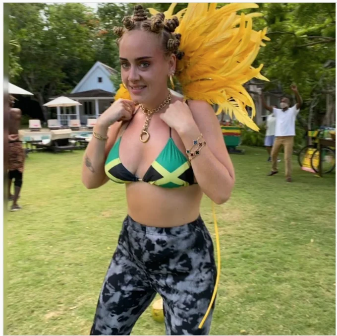 Adele's Notting Hill Carnival Photo — Full-body shot of Adele in Jamaican bikini, Bantu knots, and yellow carnival feathers