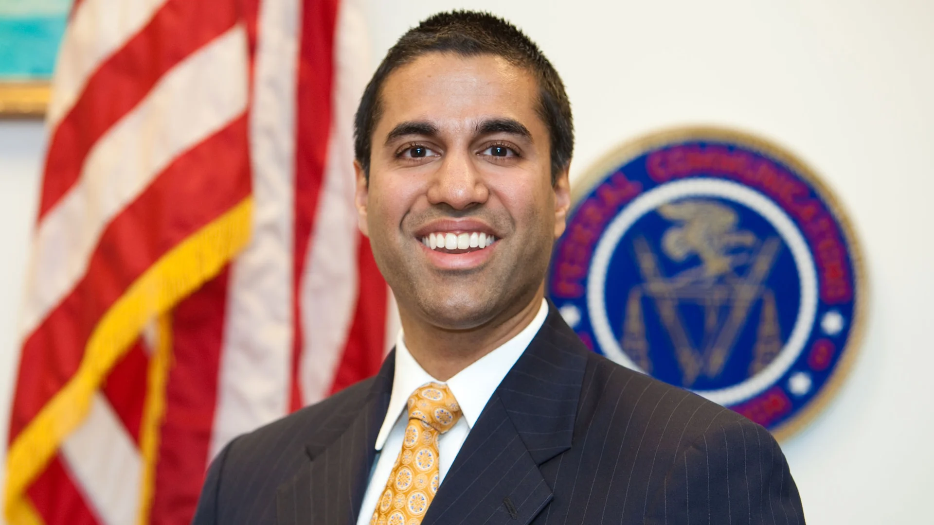 Ajit Pai official FCC portrait in front of American flag and FCC seal