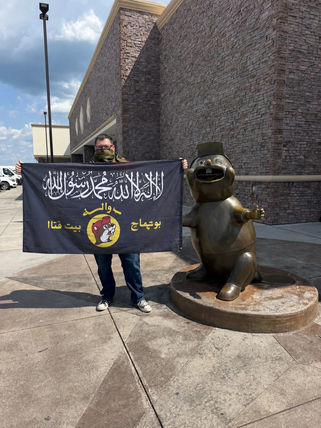 Al Buqqi — Person holding al-Buqqi flag next to bronze Buc-ee's beaver statue outside a store