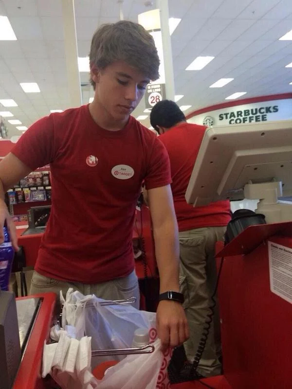 Alex From Target — Teenage Target employee with styled hair bagging items at a store checkout