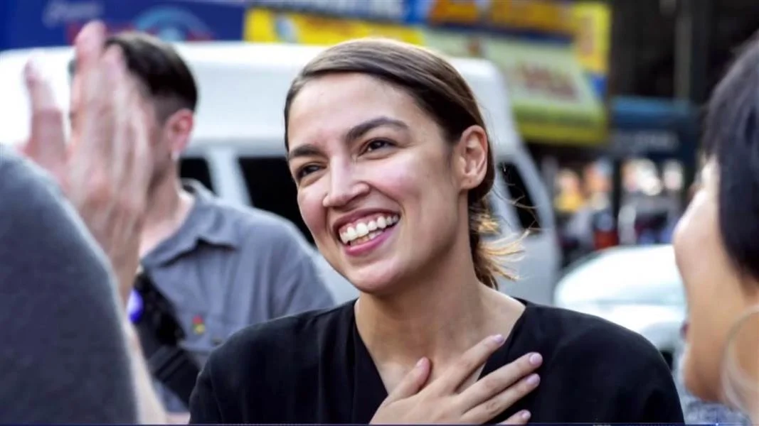 Alexandria Ocasio Cortez — Alexandria Ocasio-Cortez smiling with hand over her chest during a campaign event