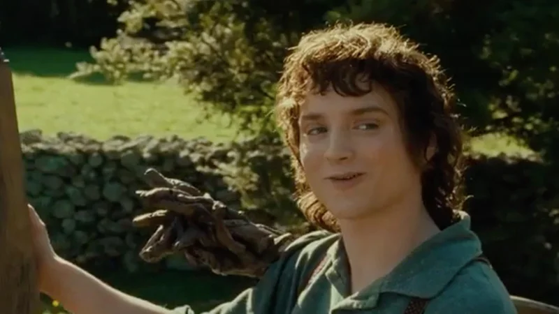 All Right Then Keep Your Secrets — Frodo Baggins smiling and raising his hand in a Shire garden, still from The Fellowship of the Ring