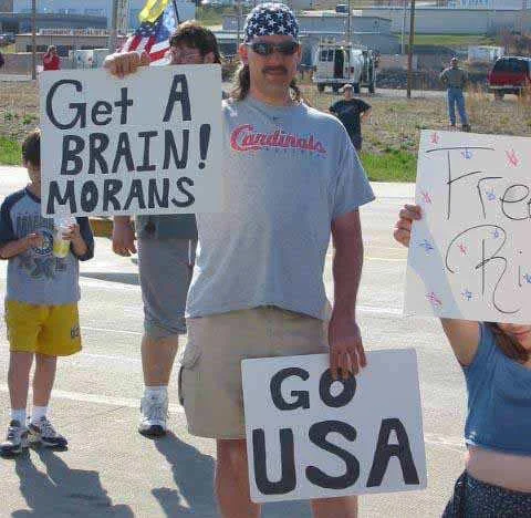 America Fuck Yeah — Man at rally holding misspelled protest sign reading Get A Brain Morans and Go USA