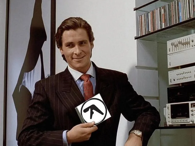 American Psycho — Patrick Bateman holding up an Aphex Twin album CD.