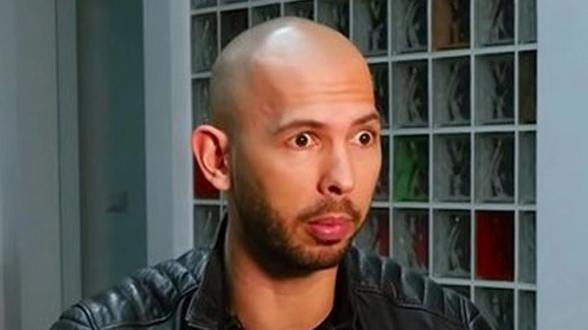 Andrew Tate Shocked Face — Andrew Tate with a shocked, wide-eyed expression in a black leather jacket.