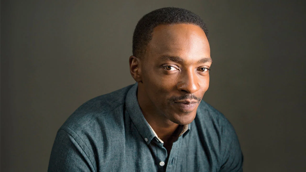 Anthony Mackie's Smirk — Anthony Mackie in a denim shirt giving a subtle sideways smirk against a dark background.