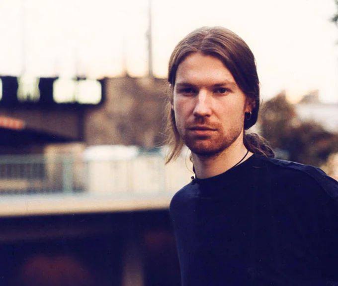 Outdoor portrait of Aphex Twin wearing a dark shirt in an urban setting