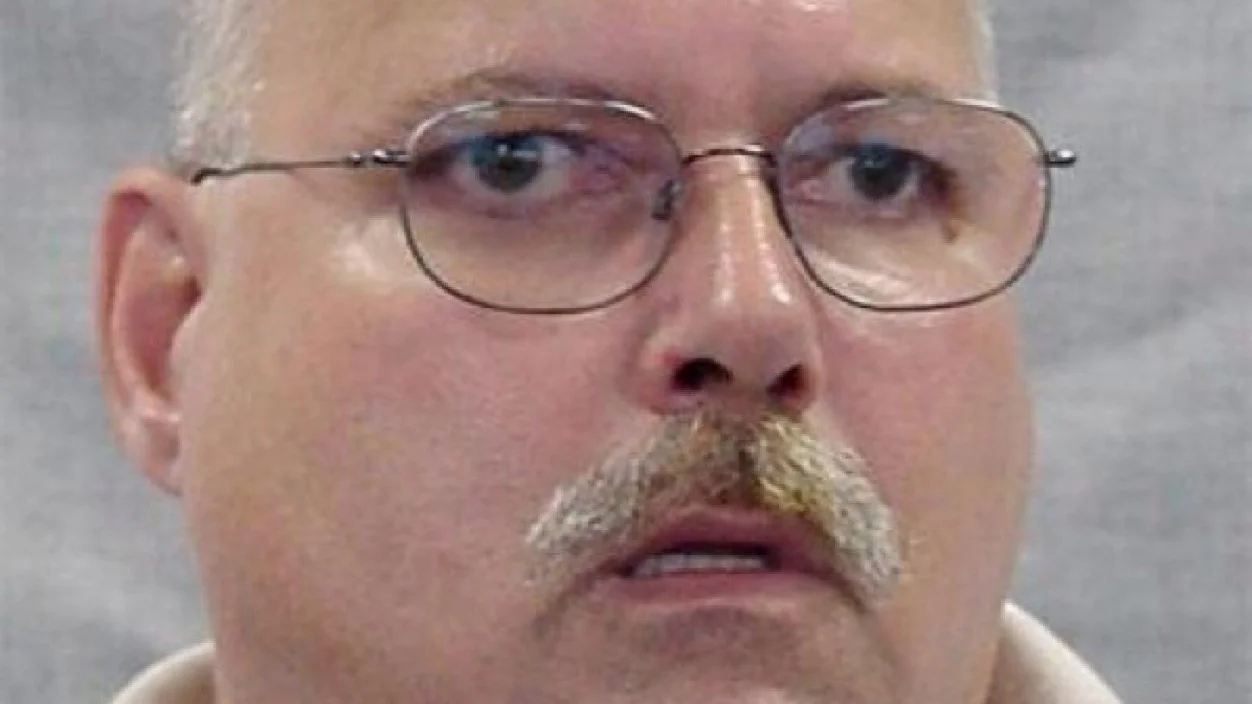 Close-up photo of a bald mustached man with glasses staring blankly, the source image of the Are You a Wizard meme
