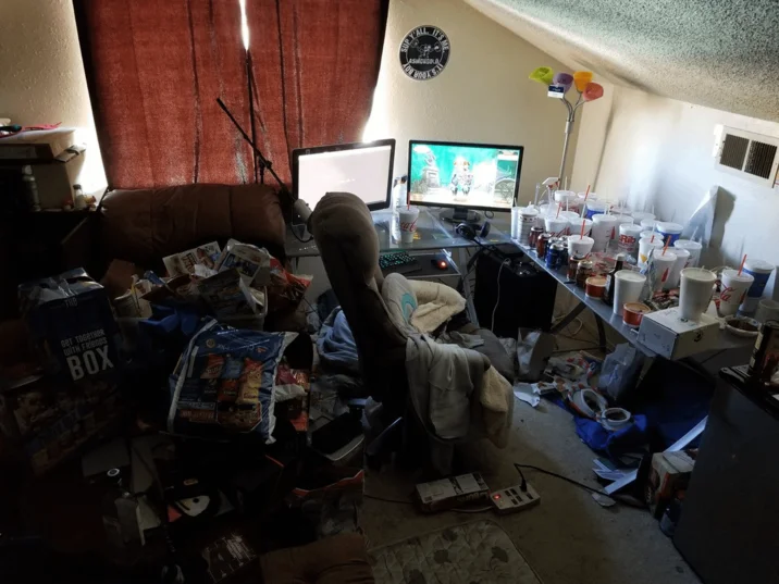 Asmongold's Bedroom — Interior photo of Asmongold's cluttered room with dual monitors and piles of trash