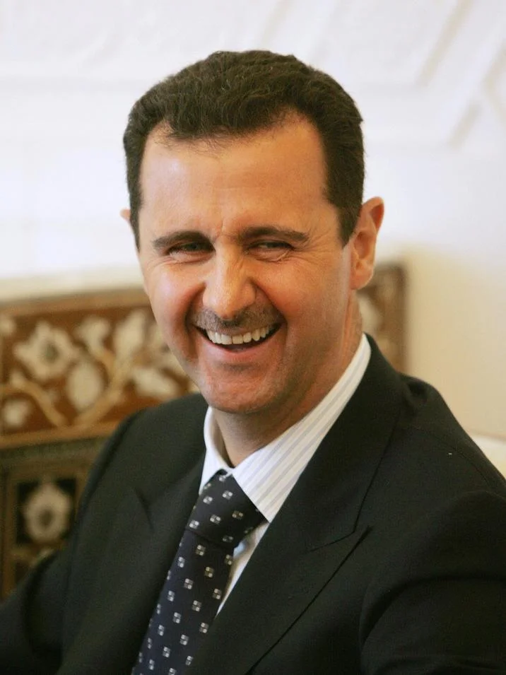 Assad Must Go — Bashar al-Assad laughing in dark suit