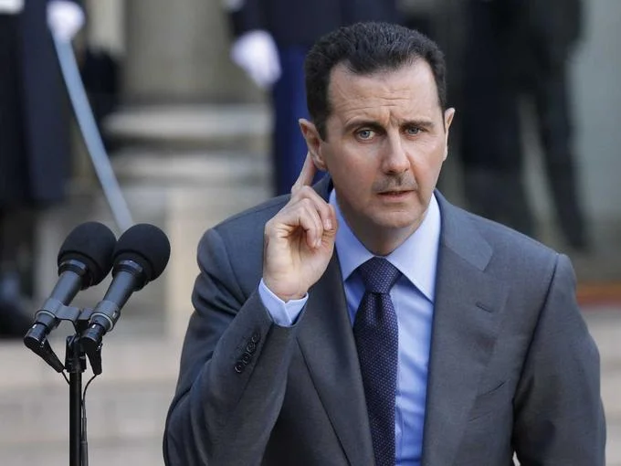 Assad Must Go — Bashar al-Assad at press conference with finger to ear