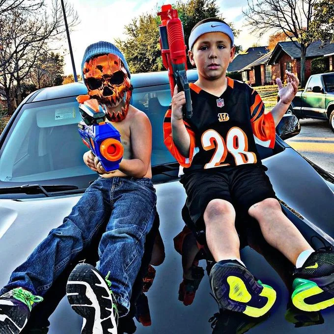Baby Gronk — Two young athletes posing on vehicle in athletic gear and accessories with confident positioning.