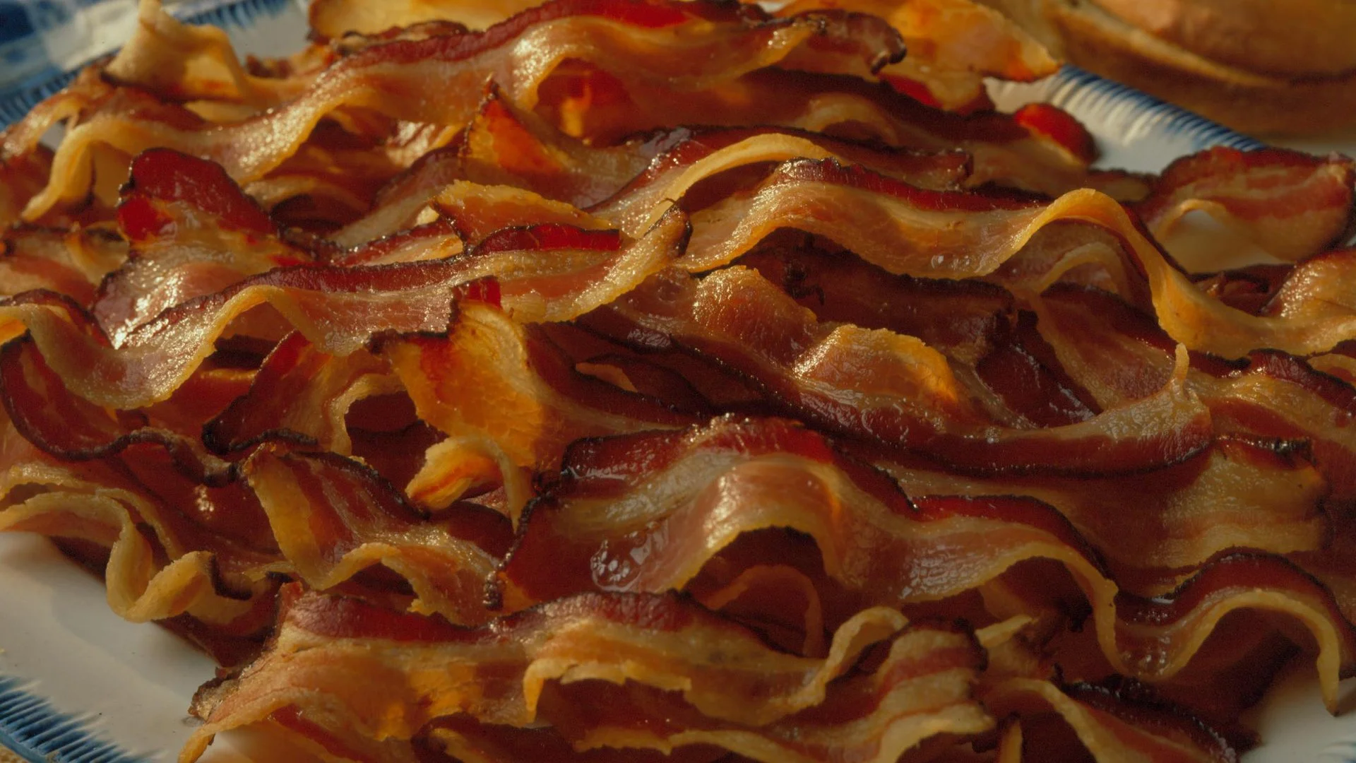 Pile of crispy cooked bacon strips on a plate