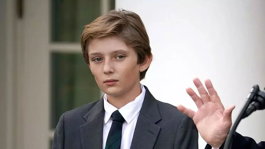 Young Barron Trump in a suit waving outside the White House