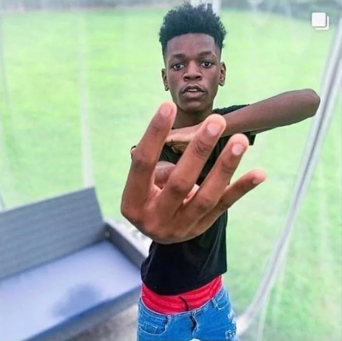 Beast Boy — Young man with afro holding up four fingers toward camera on a screened porch