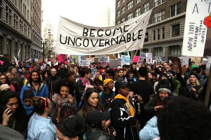 Large crowd with a 'Become Ungovernable' protest banner