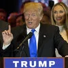 Bigly — Photo of Donald Trump speaking at a political rally wearing a blue tie with TRUMP campaign signage visible.