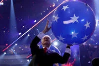 Bill Clinton Loves Balloons — Bill Clinton raises a large blue star-decorated balloon triumphantly overhead in a darkened arena during the 2016 Democratic