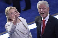 Bill Clinton Loves Balloons — Hillary Clinton in a colorful patterned outfit and Bill Clinton in a dark suit stand together on the DNC stage, with Hillary