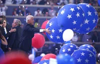 Bill Clinton Loves Balloons — Two figures navigate a stage covered in dozens of large blue and red star-patterned balloons at the 2016 Democratic National