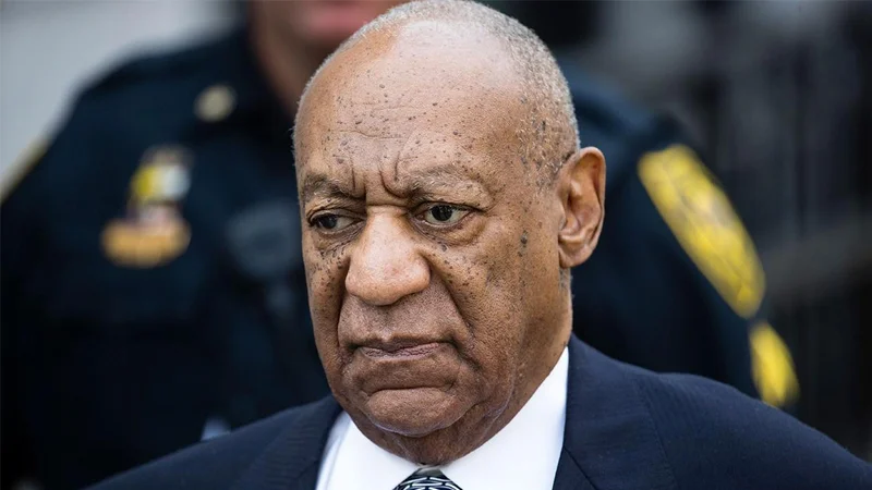 Bill Cosby Rape Allegations — Bill Cosby with a stern expression standing outside a courthouse near police officers