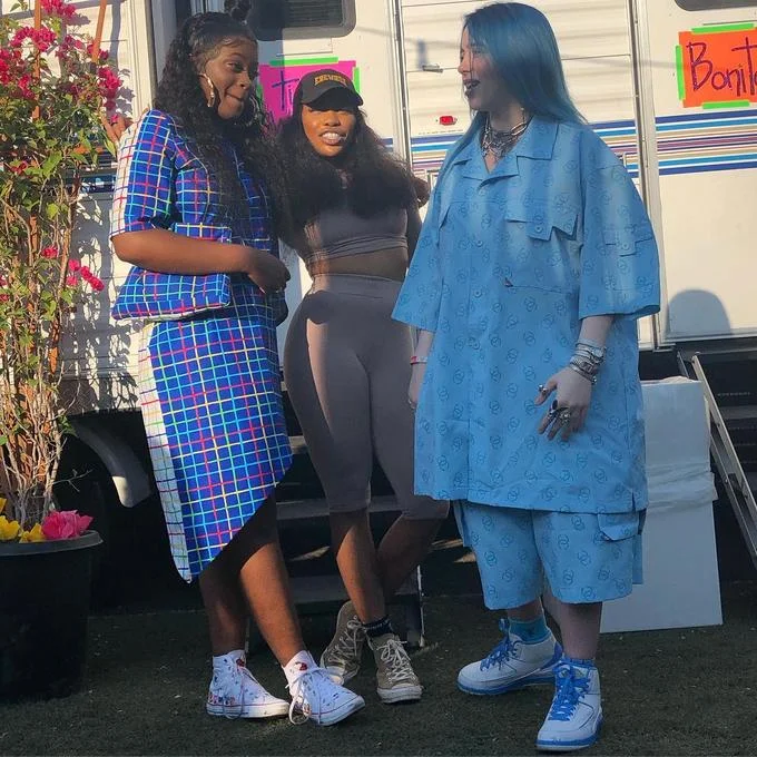 Billie Eilish in oversized blue outfit standing with two friends