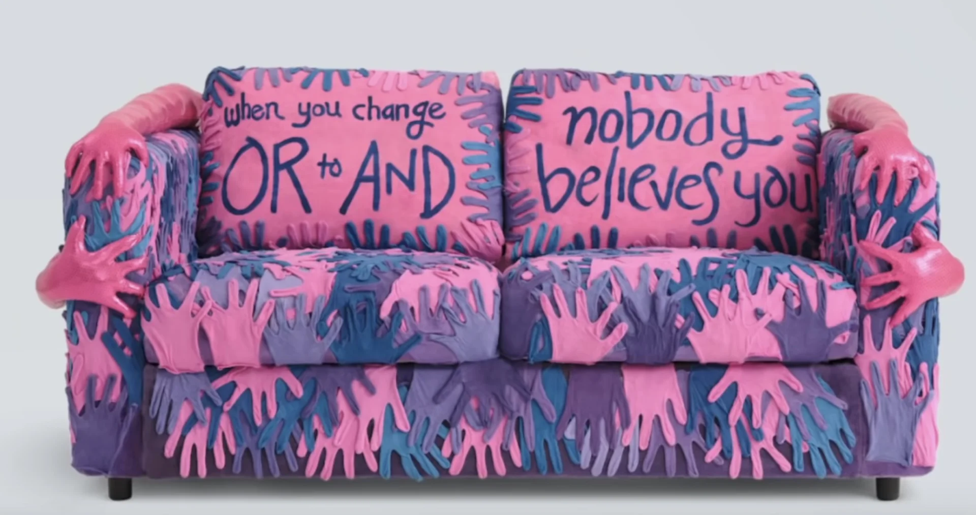 Bisexual Couch — Pink, purple, and blue couch covered in handprints with text about bisexual erasure on the cushions.