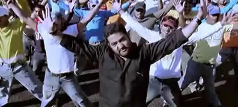 Bollywood Movie Dance Remixes — A dynamic Bollywood movie dance scene featuring a central male performer with both arms raised triumphantly, surrounded by a