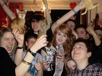 A lively party photograph with cats digitally integrated among celebratory guests, strategically placed consistent with the boozecats format.