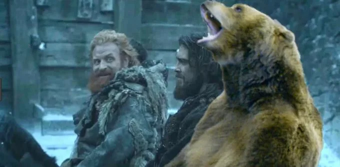 Brienne And Tormund — A Game of Thrones scene still showing Tormund Giantsbane laughing widely next to a large brown bear and another wildling in snowy setting.