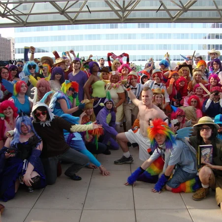 Group of bronies in colorful My Little Pony cosplay posing together at a convention