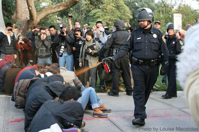 Casually Pepper Spray Everything Cop — The original news photograph by Louise Macabitas showing a UC Davis police officer casually pepper spraying seated
