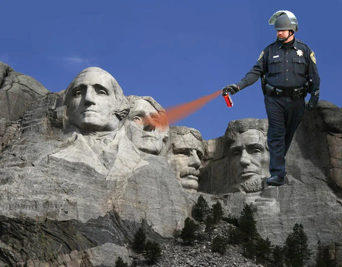 Casually Pepper Spray Everything Cop — The pepper spray cop scaled up and placed atop Mount Rushmore spraying the carved presidential faces.