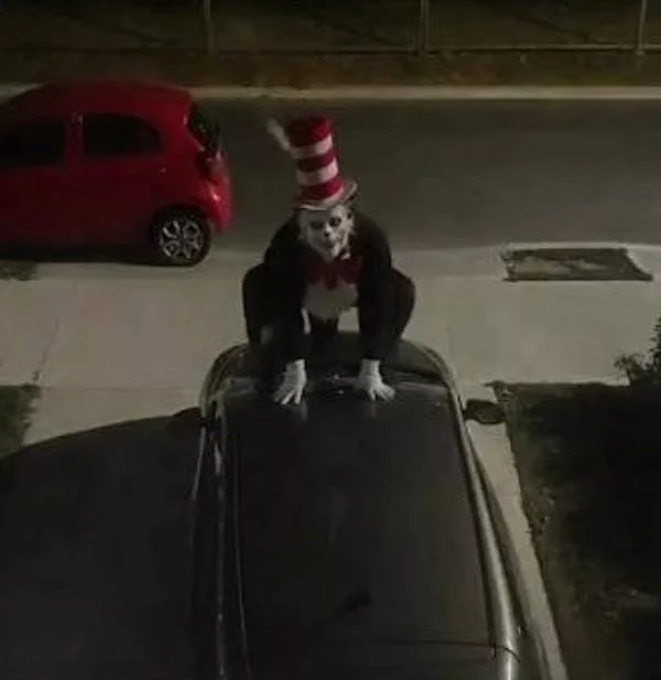 Cat In the Hat Serial Killer Trend — Person in Cat in the Hat costume crouched on top of a car at night.