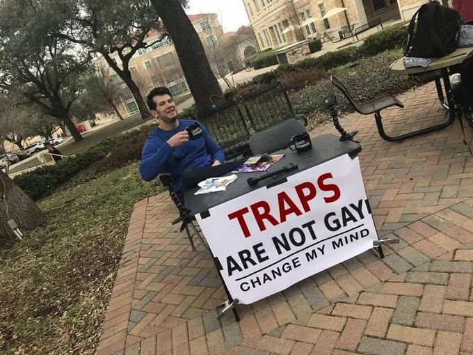 Steven Crowder's sign displays TRAPS ARE NOT GAY CHANGE MY MIND in black text.