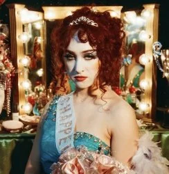 Chappell Roan — Glamorous portrait with voluminous red curly hair with accessories against ornate lighting.