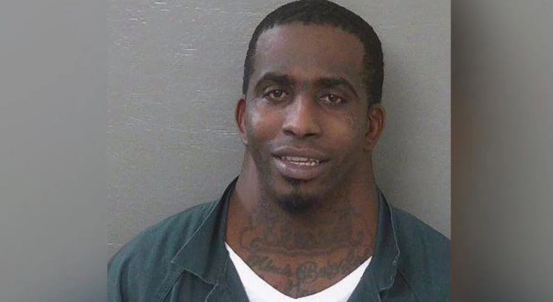 Charles Mcdowells Wide Neck Mugshot — Charles McDowell mugshot showing his wide neck in a green prison jumpsuit against a gray wall