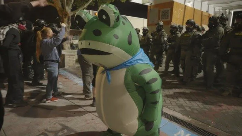 Chinese Frog Mascot — Person in inflatable frog costume at Portland protest with police in background