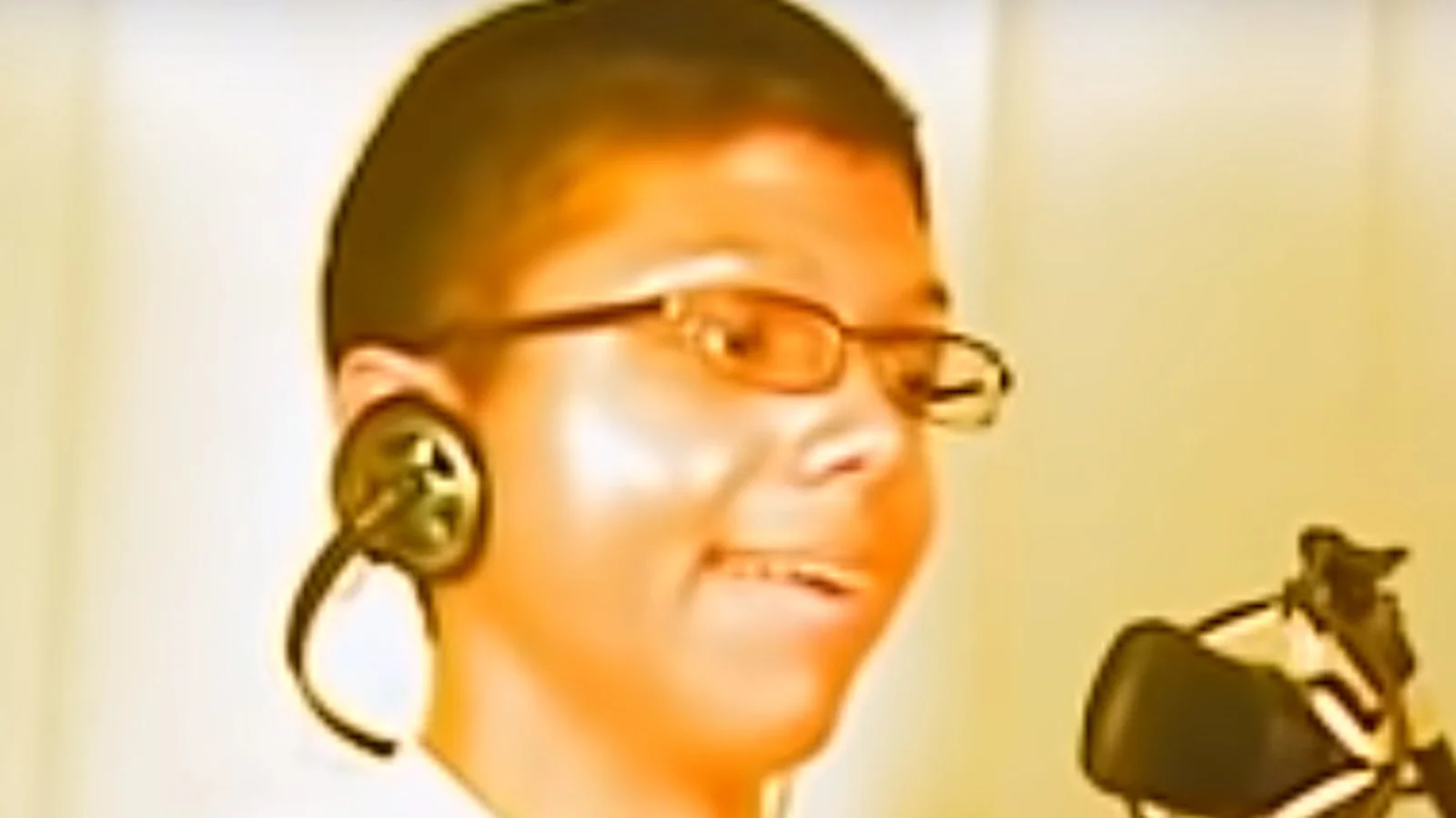 Tay Zonday singing at a microphone wearing headphones and glasses, captured from the original 2007 Chocolate Rain music video.