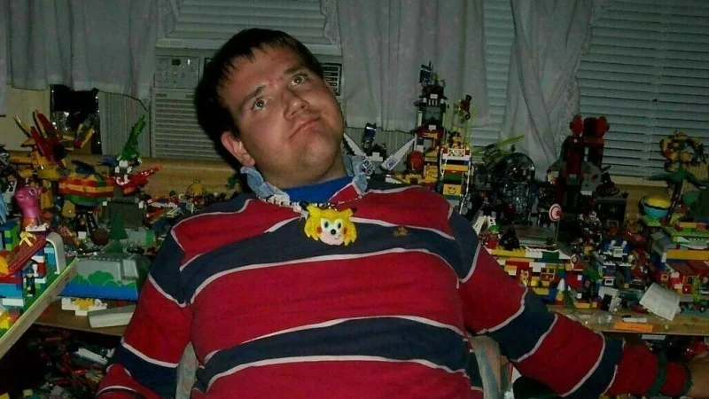 Chris Chan Cwc Christian Weston Chandler — Chris Chan in striped shirt with Sonichu medallion surrounded by Lego builds