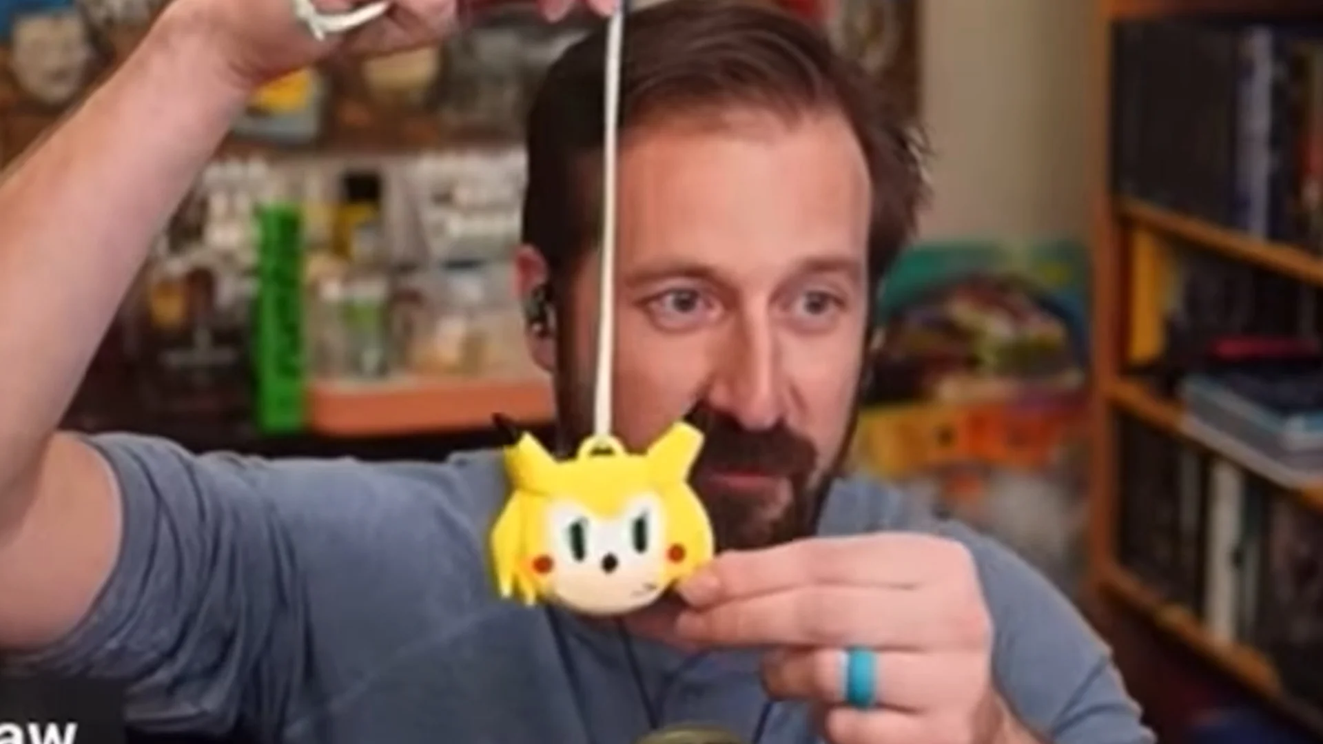 Chris Chan's Sonichu Medallion Curse — Bearded man in blue shirt holding up a yellow Sonichu plush medallion by its string