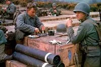 Colorized History — Colorized WWII soldiers at makeshift table surrounded by artillery shells.