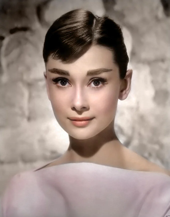 Colorized History — Luminous colorized portrait of young Audrey Hepburn in light off-shoulder top.