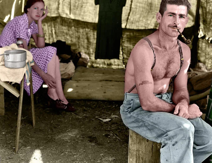 Colorized History — Colorized 1930s photograph of shirtless man with pipe near tent and woman in pink dress.
