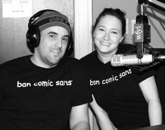 Two people in Ban Comic Sans t-shirts at radio station.