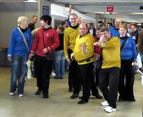 Four anime cosplayers with colorful wigs posing at a convention